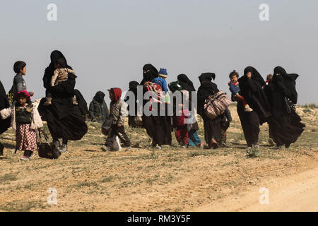 Deir Ezzor, Syrien. 12 Feb, 2019. Frauen gehen mit ihren Kindern als Zivilisten der islamische Staat fliehen - statt Dorf Baghouz im östlichen syrischen Provinz von Deir Ezzor. Mehr als 1.500 Menschen haben im vergangenen pocket Islamischen Staat im östlichen Syrien in den letzten 48 Stunden Links zu fliehen, die Schlacht zwischen den Kämpfern der syrischen Demokratischen Kräfte (SDF), einer von den USA unterstützten Kurdischen-Gruppe führte, und der Islamischen Staat. Credit: Aboud Hamam/dpa/Alamy leben Nachrichten Stockfoto