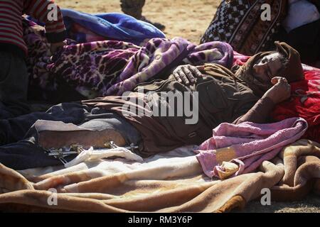 Deir Ezzor, Syrien. 12 Feb, 2019. Ein schwer verletzter Mann auf dem Boden liegt als Zivilisten der islamische Staat fliehen - statt Dorf Baghouz im östlichen syrischen Provinz von Deir Ezzor. Mehr als 1.500 Menschen haben im vergangenen pocket Islamischen Staat im östlichen Syrien in den letzten 48 Stunden Links zu fliehen, die Schlacht zwischen den Kämpfern der syrischen Demokratischen Kräfte (SDF), einer von den USA unterstützten Kurdischen-Gruppe führte, und der Islamischen Staat. Credit: Aboud Hamam/dpa/Alamy leben Nachrichten Stockfoto