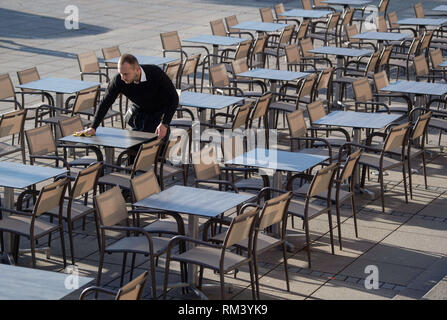 Stuttgart, Deutschland. 13 Feb, 2019. Ein Mitarbeiter eines Café auf dem Schlossplatz reinigt die Tabellen der Außenbereich des Restaurants. Credit: Marijan Murat/dpa/Alamy leben Nachrichten Stockfoto