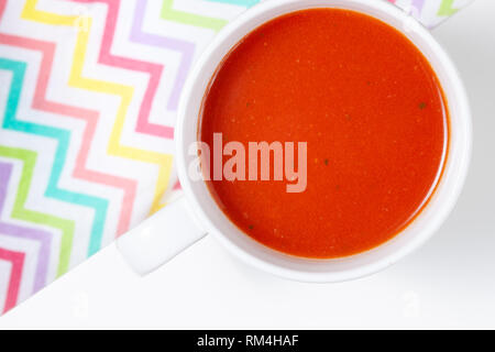 Schüssel mit Tomatensuppe auf weißem Hintergrund mit Schatten, Ansicht von oben isoliert Stockfoto