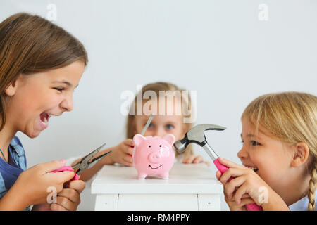 Kinder mit Schraubendreher, Zange und Hammer durch den Pink Pig piggy Bank auf weißem Hintergrund Stockfoto