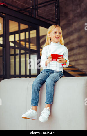 Positiv erfreut Kind im Wohnzimmer sitzen Stockfoto