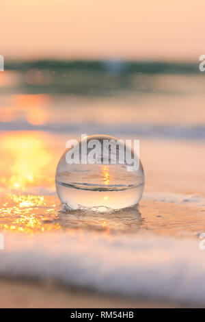 Crystal Linse Kugel- oder Glaskugel am Strand bei Sonnenuntergang Stockfoto