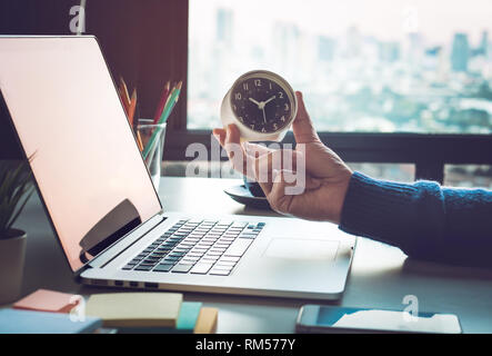 Business Konzepte mit Geschäftsmann halten Sie Clock auf dem Computer Laptop. Für Investitionen Analyse, Warten auf Erfolg Ideen Stockfoto