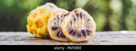 Frisches Obst und Noni noni Slice auf Holz- Hintergrund und Raum. Scheibe der Noni-Frucht mit Platz auf Holz- hintergrund Banner, lange Format Stockfoto