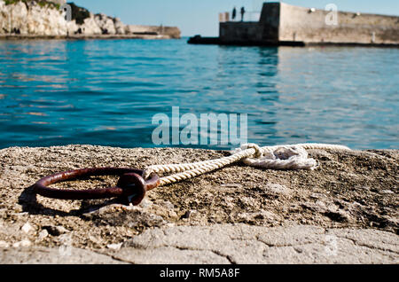 Rusty Ring mit weißen Seil in einem Dock entlang dem Mittelmeer Stockfoto