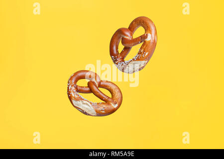 Flying Food Bäckerei Konzept Deutschen traditionellen Gesalzen Brezel auf gelbem Hintergrund Stockfoto