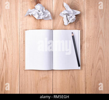 Öffnen Notebook in einer Zelle und schwarzem Holz Bleistift auf einem hölzernen Hintergrund Stockfoto