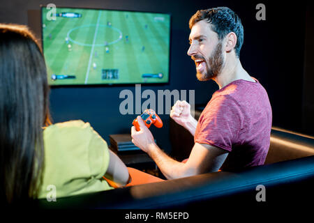 Junge aufgeregt paar Fußball spielen Spiel mit Spielkonsole sitzen auf der Couch am Spielen Club Stockfoto