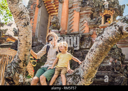 Vater und Sohn Reisende, die auf dem Hintergrund der Pura Taman Saraswati Kemuda Tempel in Ubud, Bali, Indonesien BANNER, lange Format mit Reisen Stockfoto