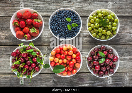 Frische Beeren in eine Schüssel. Vielzahl von Beerenobst auf Tabelle, Ansicht von oben, flach. Stockfoto