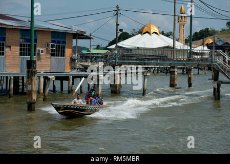 Schnellboot Wassertaxi, Gehweg und Hütten auf Stelzen in Brunei River mit Moschee im Hintergrund, Wasser Dorf (Kampong Ayer), Bandar Seri Begawa Stockfoto