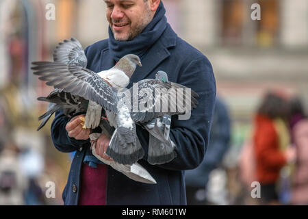 Tauben halten in ihren Händen auf dem Dam Platz in Amsterdam Die Niederlande 2019 Stockfoto