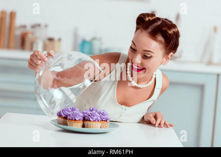 Ziemlich Pin-up-Girl an Platte voll mit hausgemachten Kuchen auf der Suche Stockfoto