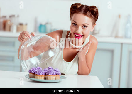 Lächelnd Pin up Girl zeigt Teller voll mit hausgemachten Kuchen Stockfoto
