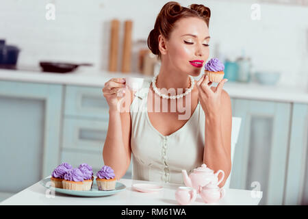 Pin-up-Girl holding Tasse Kaffee und hausgemachten Kuchen mit geschlossenen Augen Stockfoto