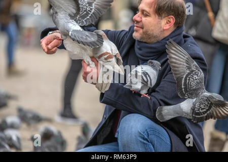 Tauben halten in ihren Händen auf dem Dam Platz in Amsterdam Die Niederlande 2019 Stockfoto