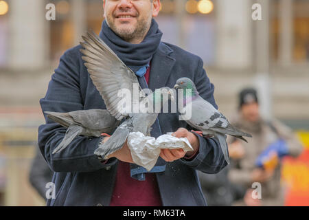 Tauben halten in ihren Händen auf dem Dam Platz in Amsterdam Die Niederlande 2019 Stockfoto