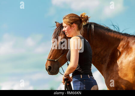 Junge Frau Mädchen kümmert sich um braunen Pferd. Frau mit Tier im Freien. Stockfoto