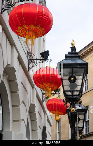 Chinesische rote und goldene Laternen, die an einem Gebäude mit altmodischen Lampenständern hängen, York, North Yorkshire, England, Großbritannien. Stockfoto