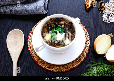 Hausgemachte vegetarische Pilzsuppe mit Graupen und Gemüse in eine weiße Schale mit zwei Griffen. Dill, Petersilie und Zwiebeln. Stockfoto