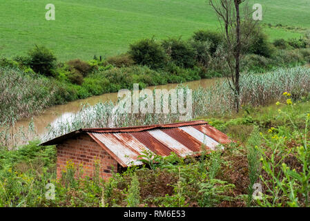 Die verrosteten Dach eines verlassenen Gebäude am Ufer der Karkloof Fluss in der Natal Midlands, Südafrika. Stockfoto