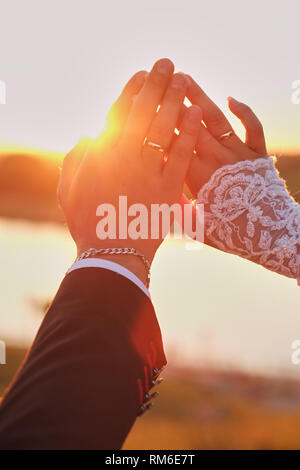 Hochzeit paar Hände, Berühren mit den Fingern in die Form. Helle Licht der Sonne im Hintergrund. Stockfoto