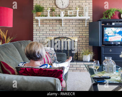 Reife Frau entspannende Fernsehen und mit einem Glas Wein, USA Stockfoto