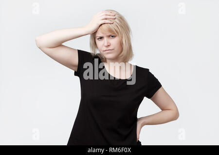 Schöne junge blonde Frau Kratzer am Kopf Stockfoto