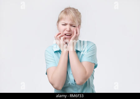 Blonde junge Frau runzelt Gesicht zu schreien, zu Unzufriedenheit Stockfoto