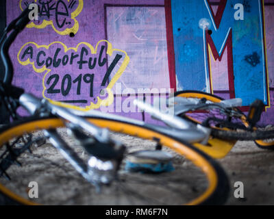 Alte gelbe Schrott, Fahrräder unter Beton Treppe mit violett Graffiti Hintergrund und Tag des neuen Jahres für eine bunte 2019 Stockfoto