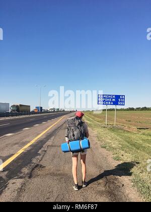 Ein reisender Mädchen mit einem Rucksack auf dem Weg geht im Sommer sonnigen Tag. Russland zurück. Stockfoto