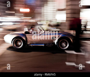 Eine männliche Fahrer eines klassischen ac cobra Muscle Car Reisen durch die Stadt New York City Stockfoto