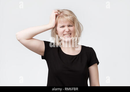 Schöne junge blonde Frau Kratzer am Kopf Stockfoto