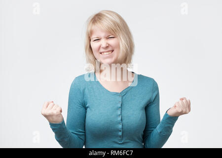 Kaukasische blonde Frau ihren Erfolg und Sieg ballte die Fäuste mit Freude Freude. Stockfoto