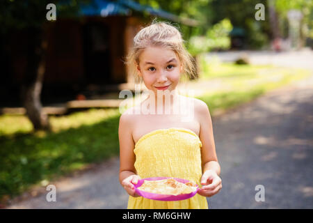 Blond lächelnde Mädchen mit Platte Pfannkuchen im Land. Stockfoto