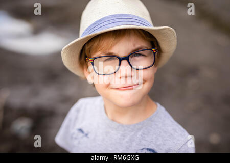 Blonde Junge mit Hut und Brille mit speziellen Linse auf dem Spielplatz. Stockfoto