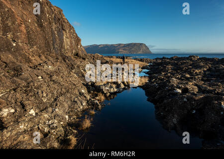 Person zu Fuß der Küste entlang von Carsaig zu Lochbuie Vergangenheit atemberaubende Rock Pools, die den blauen Himmel, Isle of Mull Küste, Schottland Stockfoto