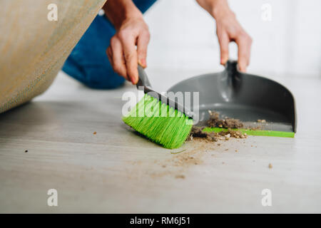 Teilweise mit Blick auf die Frau mit Besen und Schaufel reinigen Boden unter Teppich Stockfoto