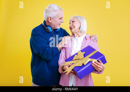 Liebevolle pensionierter Mann seine Frau vorhanden, umarmen Stockfoto