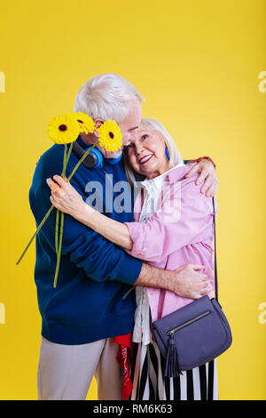Sonnenblume für Frau. Bärtige pensionierter Mann stand auf seinem Knie beim Sonnenblume präsentiert schöne Frau Stockfoto
