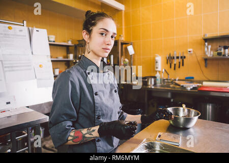 Thema Beruf und kochen Gebäck. jungen kaukasischen Frau mit Tattoo von Pastry Chef in der Küche des Restaurant Vorbereitung runde Pralinen han Stockfoto