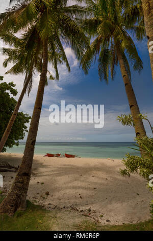 Coco Mutter Palmen Schatten zu einem weißen Sandstrand mit Booten im Hintergrund in einer ruhigen erholsamen Szene Stockfoto