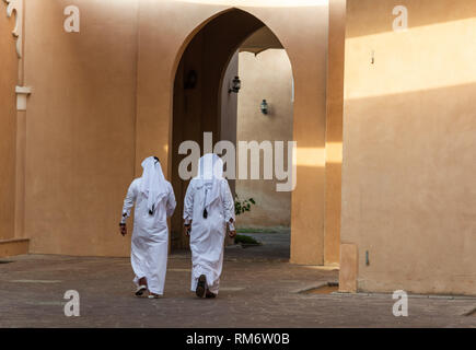 Zwei anonyme arabische Männer in weißen thobe Kleidung wandern in Doha, Katar. Stockfoto