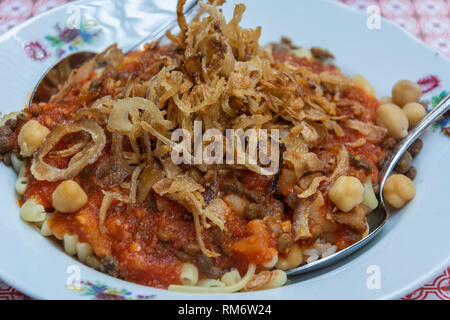 Platte der ägyptischen Gericht kushari (Nudeln, Reis, Linsen, gebratenen Zwiebeln und Tomatensoße). Stockfoto