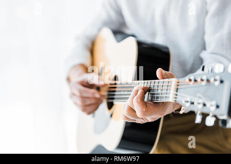 7/8-Ansicht der älteren Mann spielt akustische Gitarre zu Hause Stockfoto