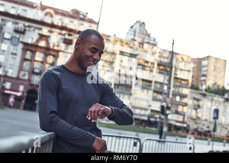 Bereit für den großen Workout jungen afrikanischen Mann ist die Überprüfung auf seine Uhr und bereit für Training in den frühen Morgen. Gesunde Gewohnheiten. Sport Konzept. Urban Workout Stockfoto