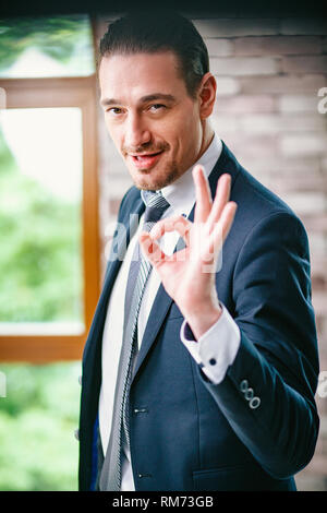 Gut aussehender Geschäftsmann zeigt ein ok Geste. Porträt Stockfoto
