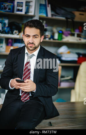 Erfolgreiche Unternehmer hält seine Telefon- und Lächeln Stockfoto