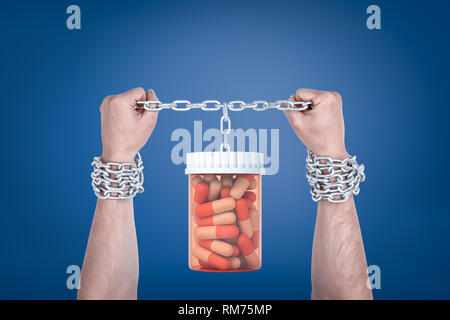 Zwei männliche Hände gefesselt Halten eines Pillen jar, die sich auf der gleichen Kette hängen. Stockfoto